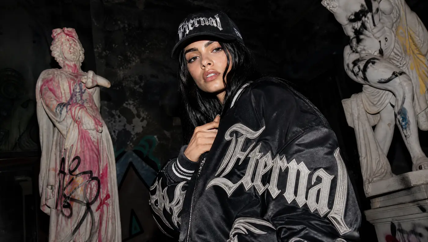 Modelo con una chaqueta bomber negra de la marca Eternal, entre estatuas
